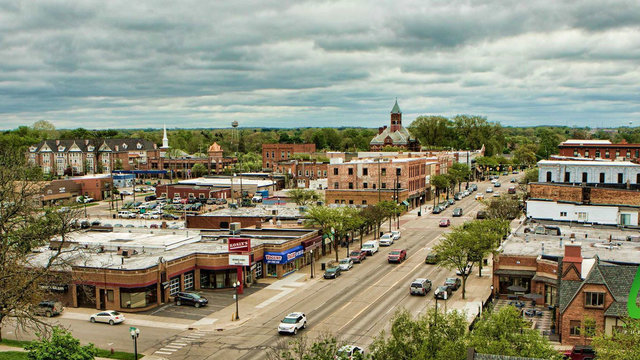 Aerial view of a small town in Michigan with a mix of commercial buildings and parked cars along a main street.