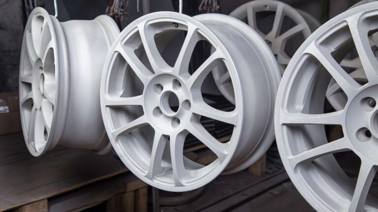 white rimmed wheels drying on rack from recent powder coating
